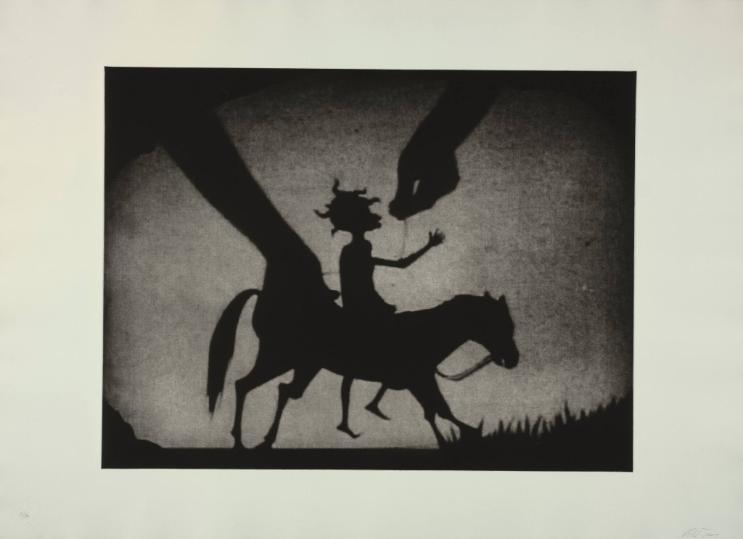 A shadow-puppet silhouette of a person riding a horse. Two hands from offscene, also shadows, are manipulating the figure.