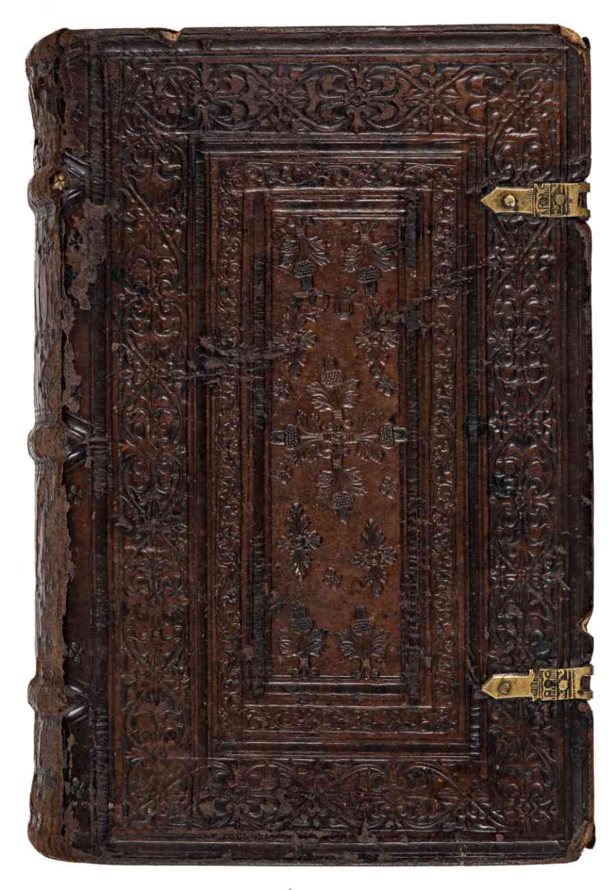 A leatherbound volume with a very intricately embossed cover and two ornate metal hinges on the right side.