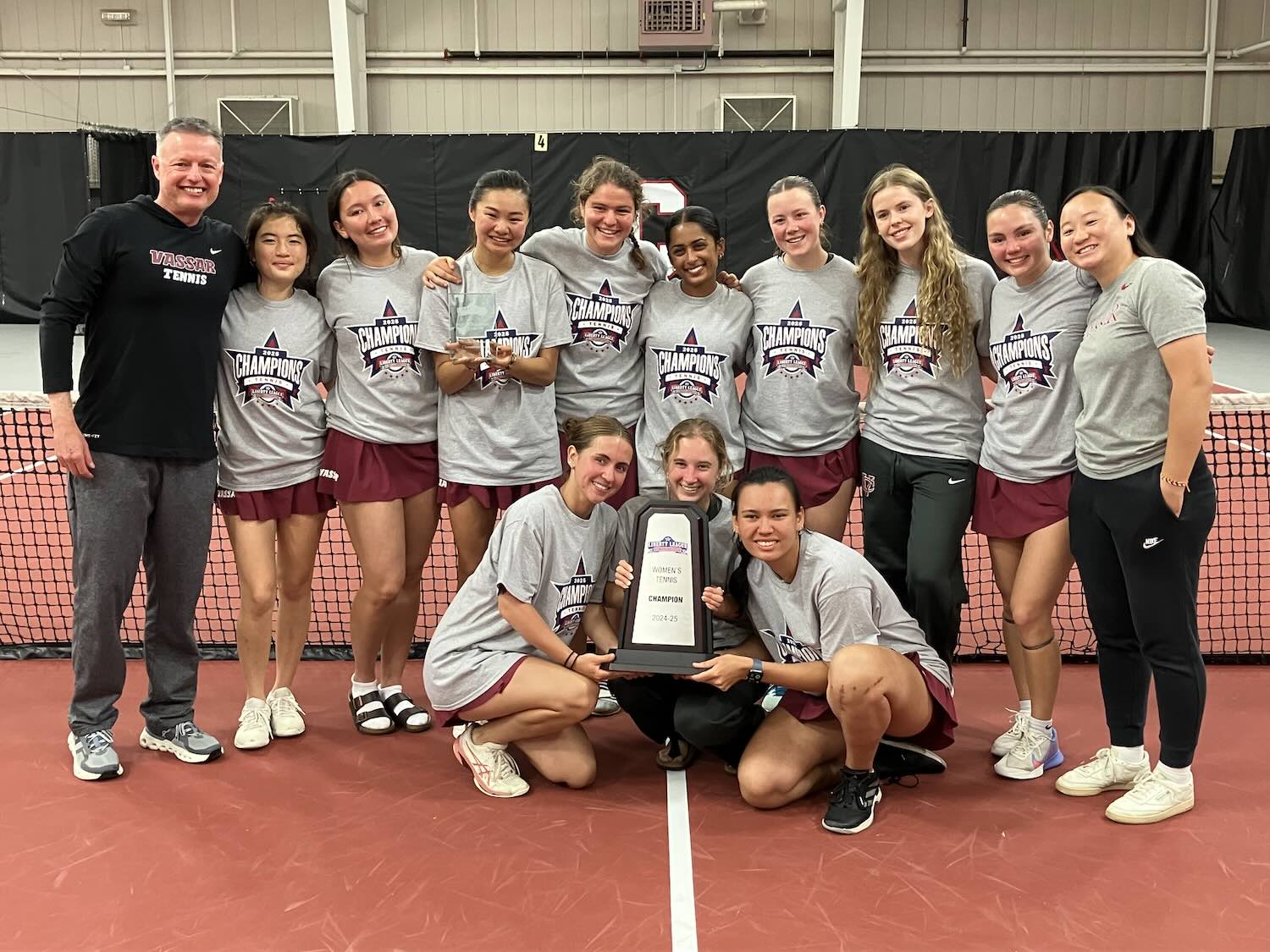 Team photo on a tennis court with a trophy.