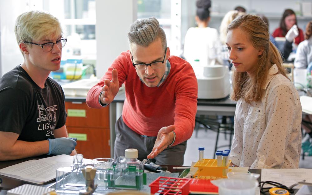 Assistant Professor of Biology and Biochemistry Colin Echeverría working in a class with two students