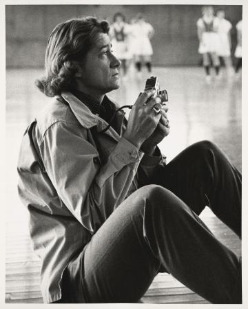 Rollie McKenna ’40 sitting on the floor holding a camera, in black and white.