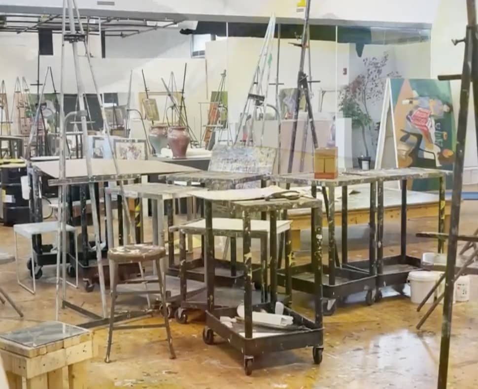 An art studio with easels, paints, stools and carts with art materials
