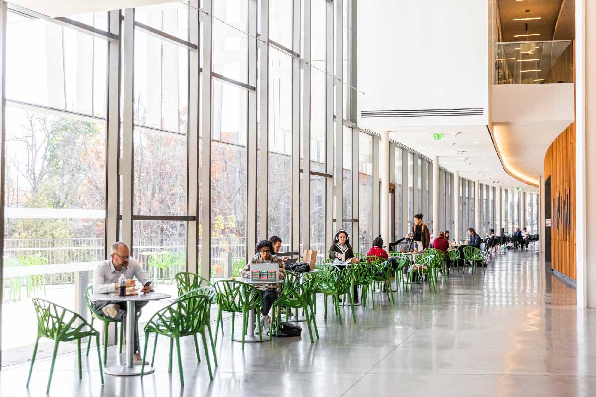 People sitting at tables and chairs in a large open space of the Bridge for Laboratory Sciences