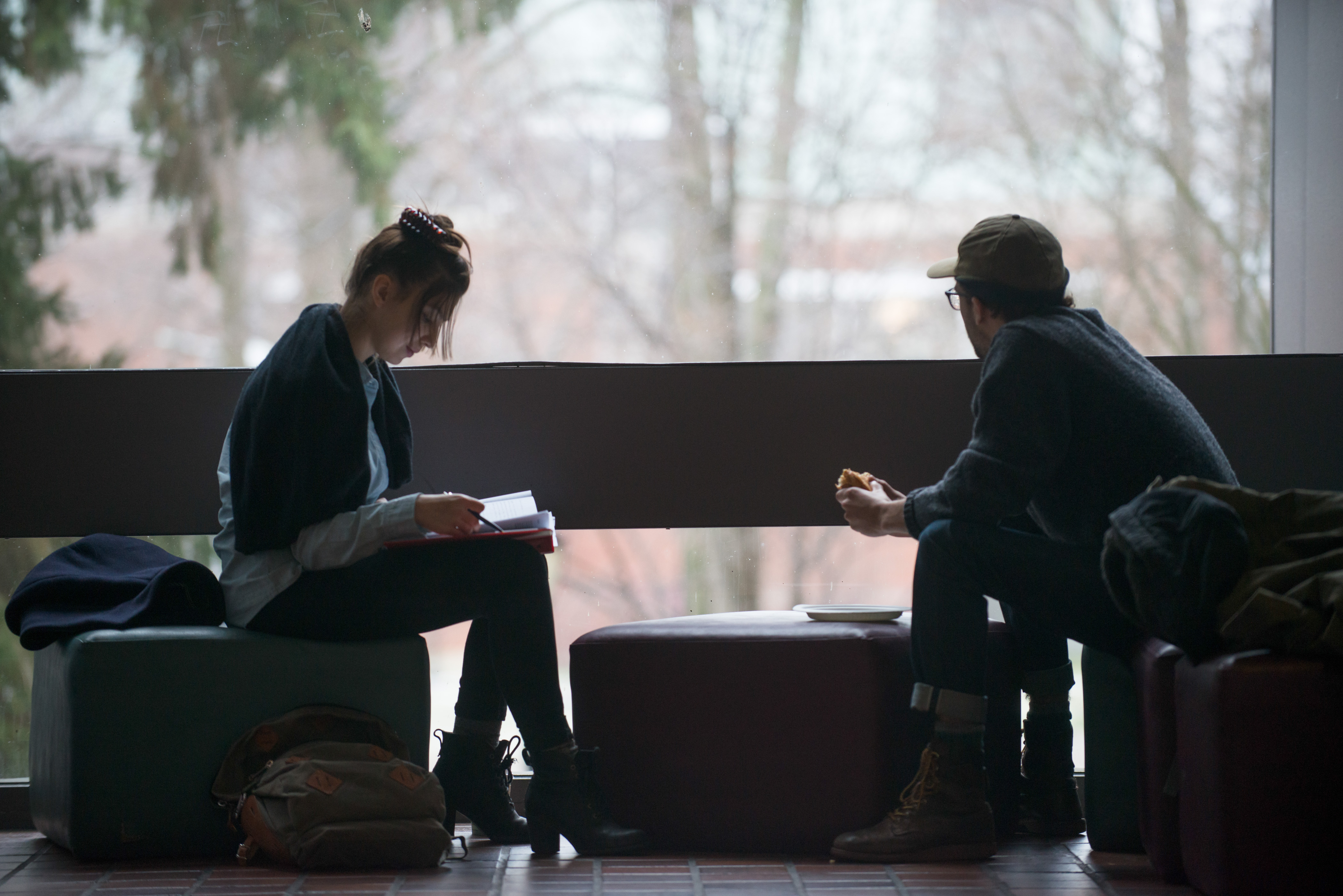 Two people, one reading, and the other looking out the window