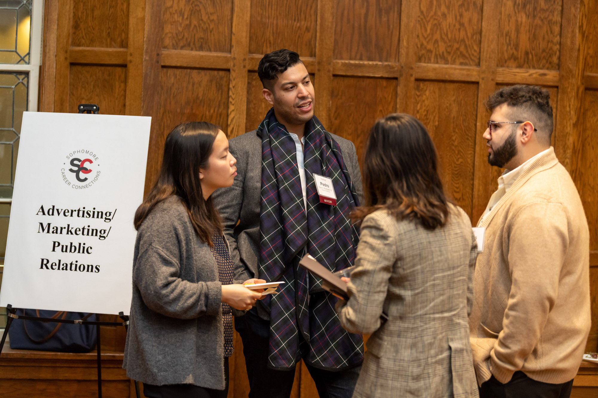 Students talk to an alumni in a wood-paneled room, the Villard Room