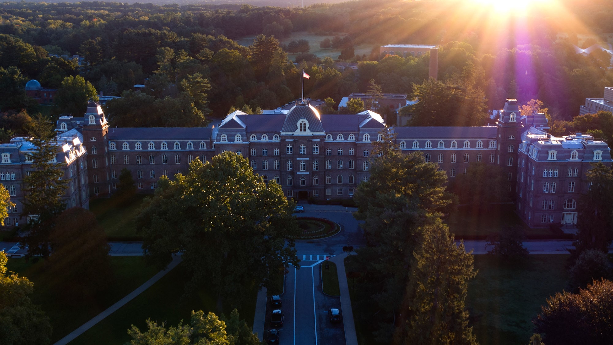 An aerial view of Main Building, a huge brick building surrounded by trees