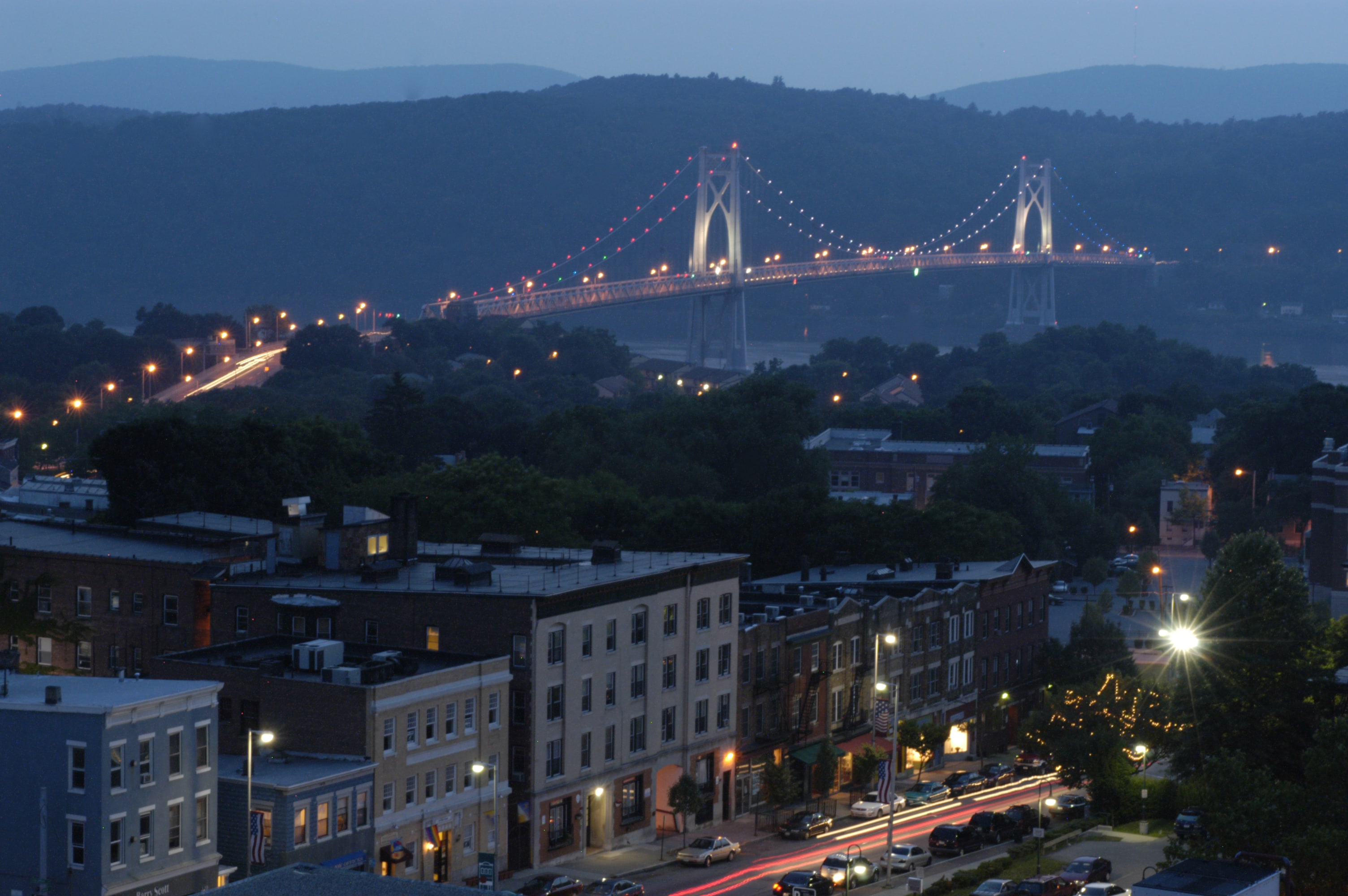 Downtown Poughkeepsie in early evening, with the Mid-Hudson Bridge illuminated in the background