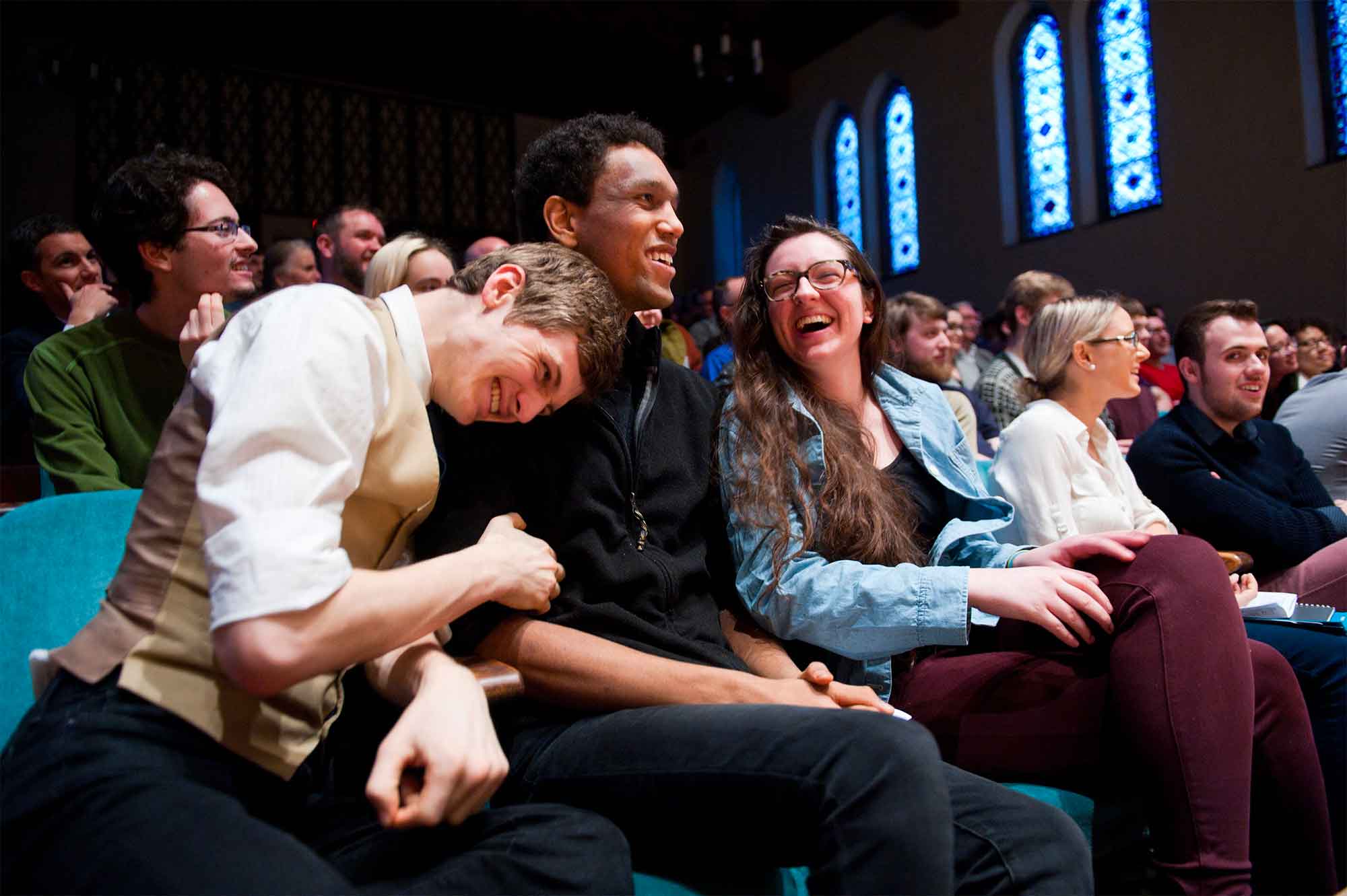 Students sit together at an event in Skinner Hall, a large room with stained-glass windows