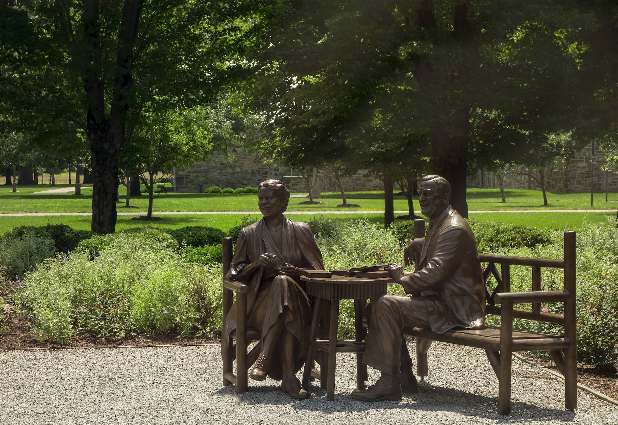 Two metal figures, sculptures of Franklin and Eleanor Roosevelt, sit in a large, outdoor space.