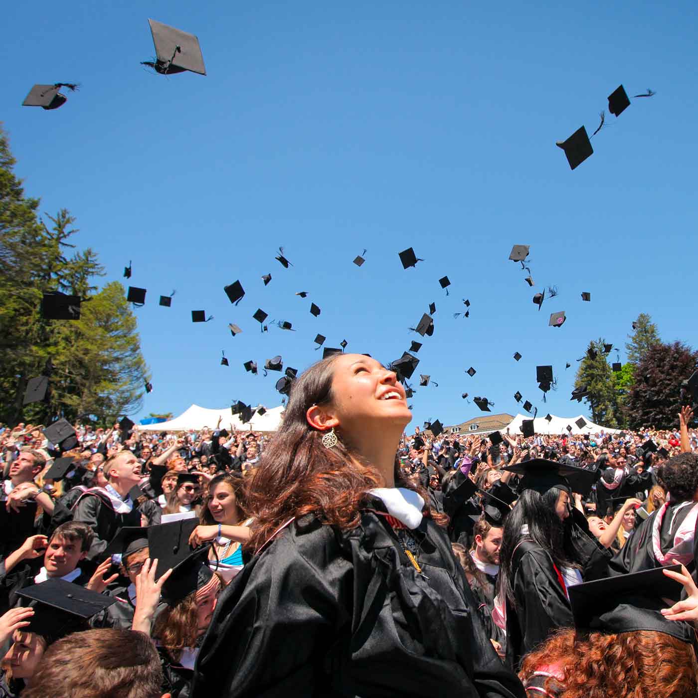 Students graduating outside and throwing their caps in the air.
