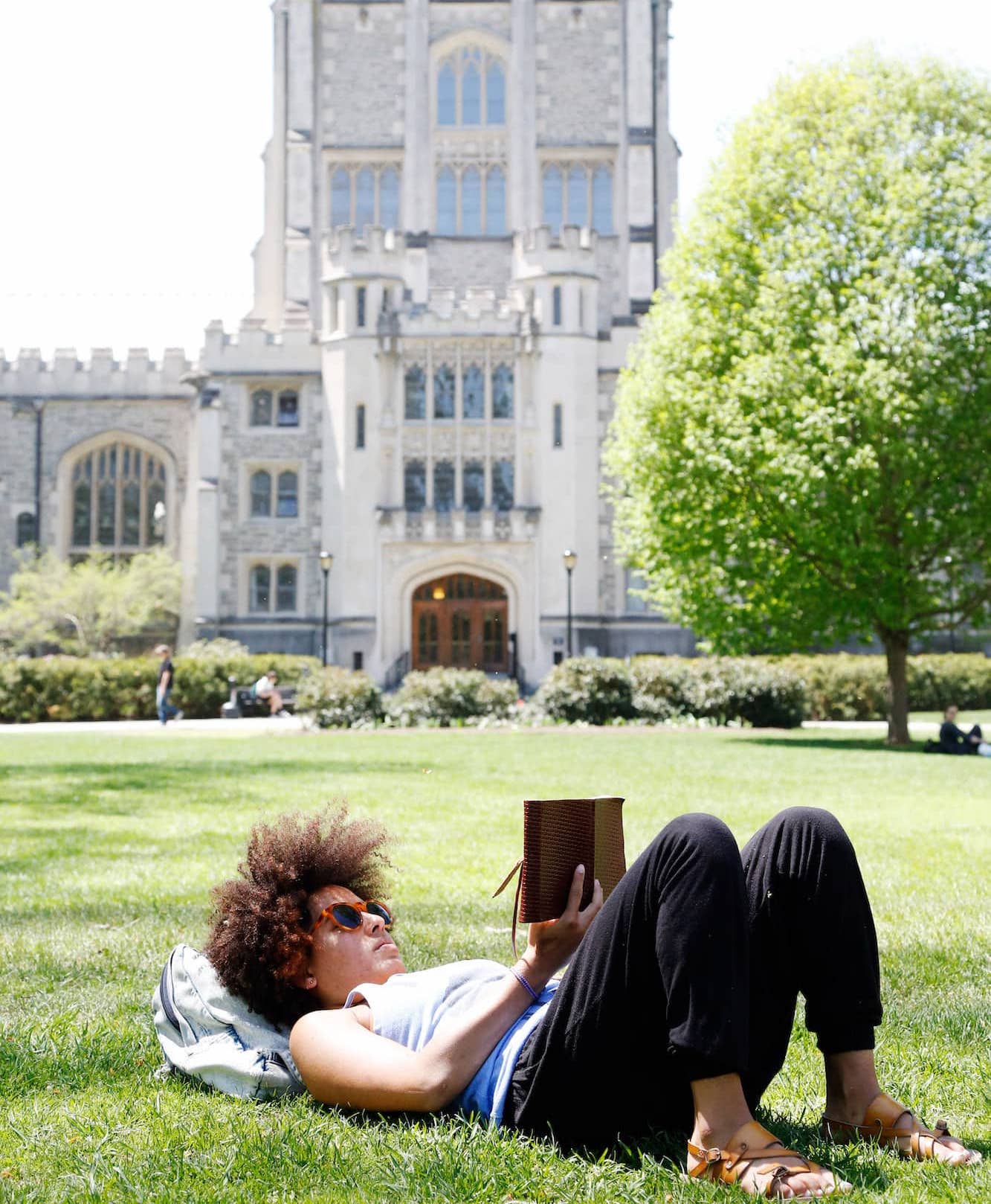 Student laying on lawn reading in front of Thompson Library on Vassar Campus