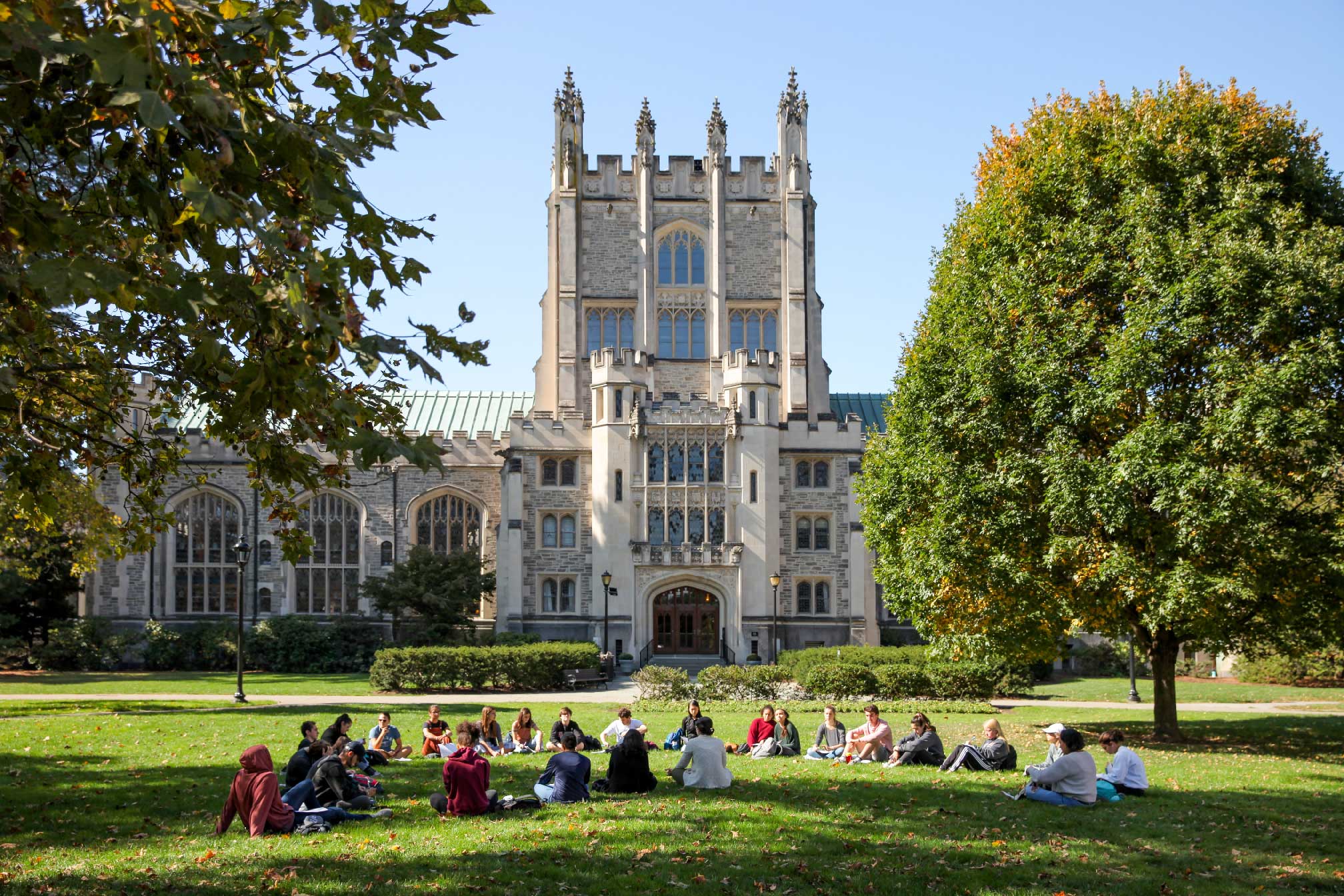 Large group of students seated on a lawn in front of the Thompson Memorial Library on Vassar campus