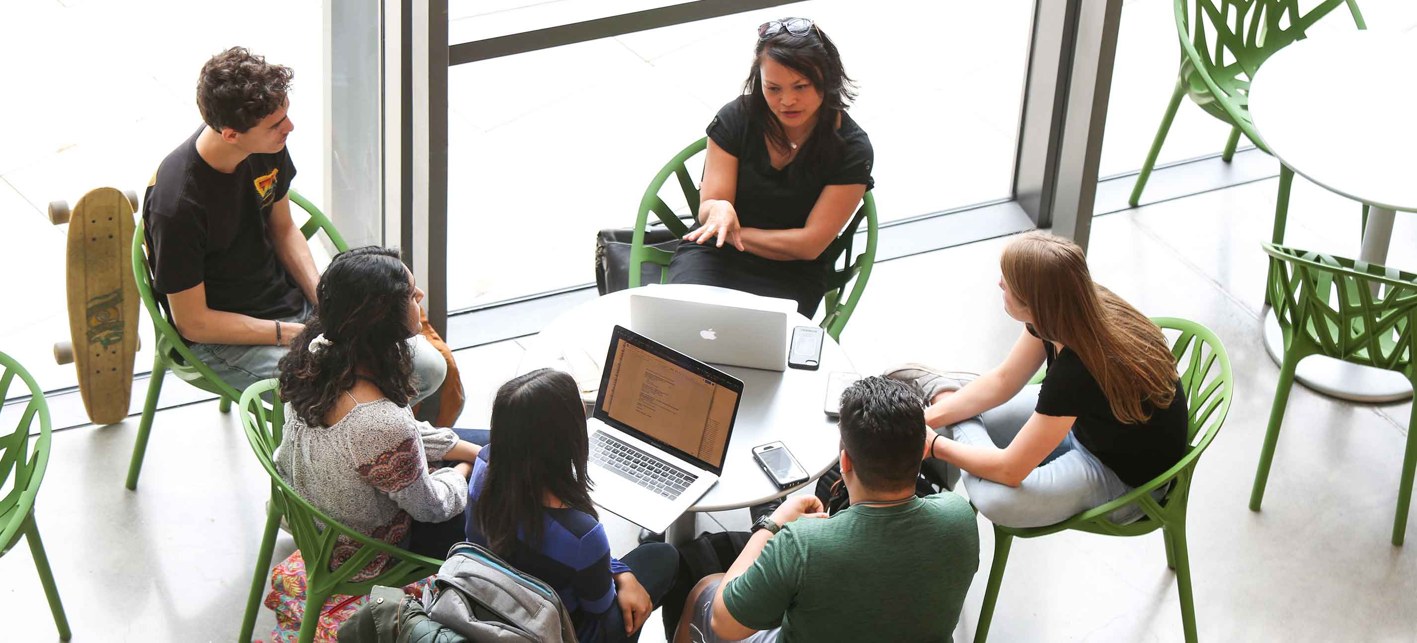 Students sit with a faculty member at a round table in the main hallway of the Bridge for Laboratory Sciences