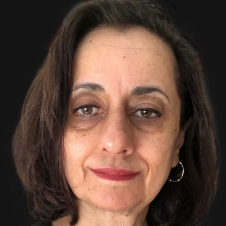 Rachna Vaid, a composed person with shoulder-length brown hair, wearing hoop earrings and red lipstick.