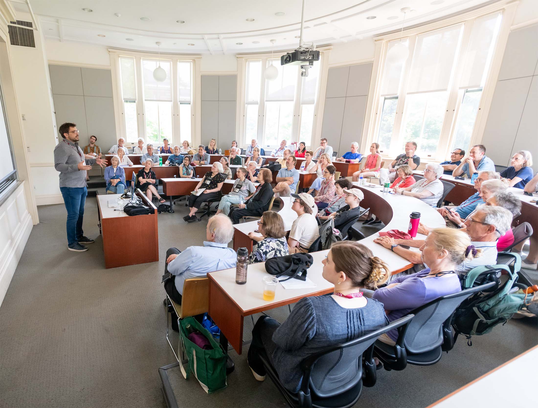 A professor presents to a full lecture hall in a tiered classroom.