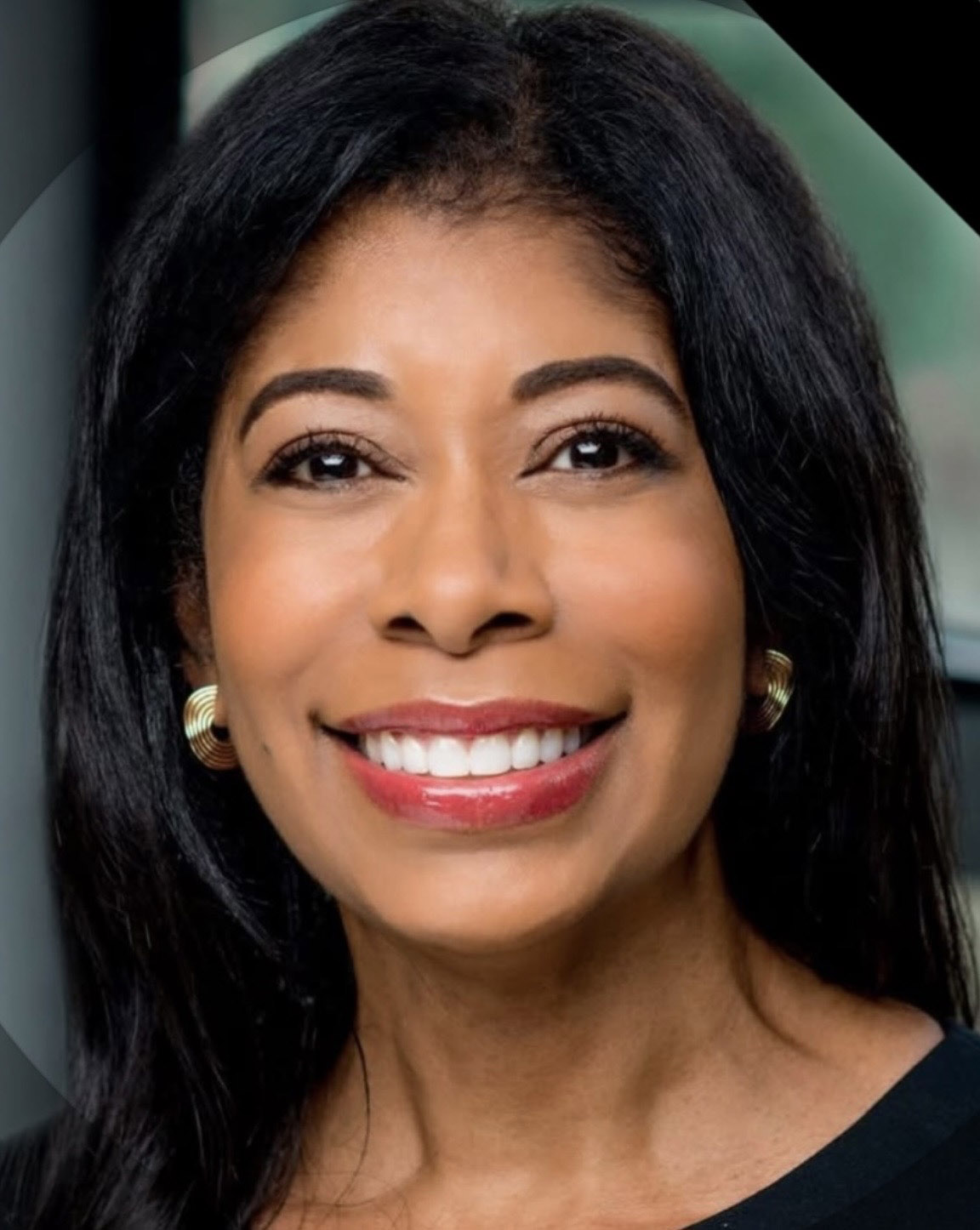 Tracy Elise Poole ’82, a person with long dark hair and gold earrings smiling in a close-up portrait.