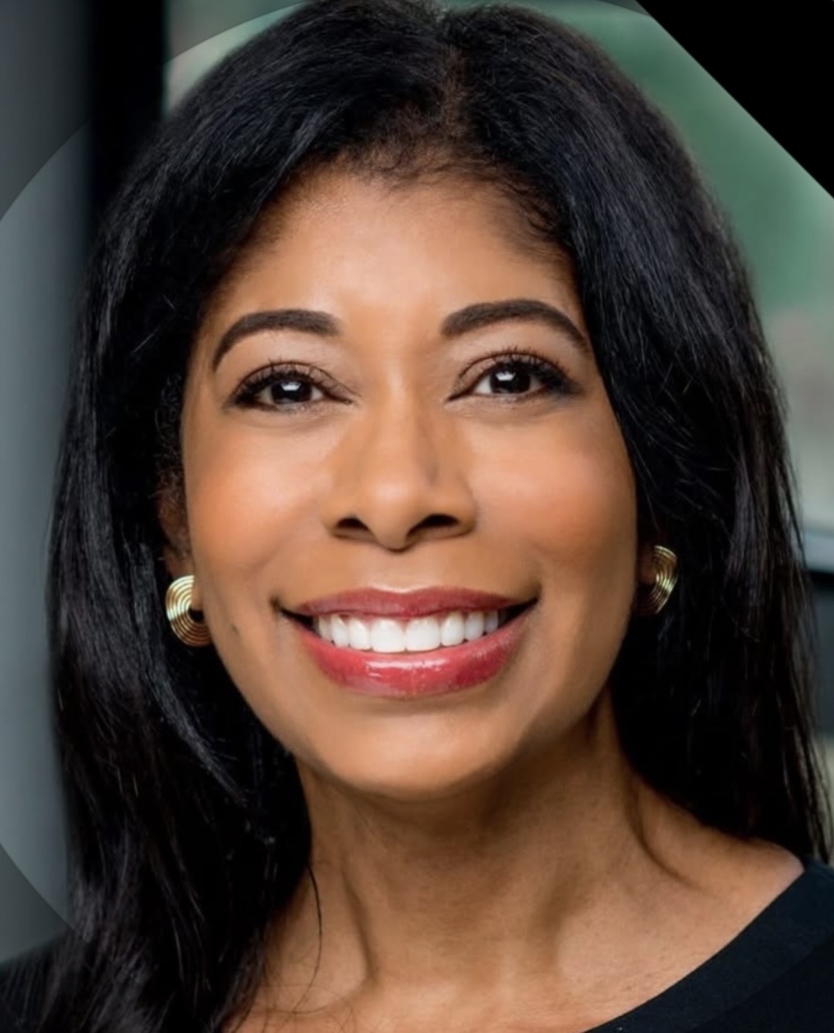 Tracy Elise Poole ’82, a person with long dark hair and gold earrings smiling in a close-up portrait.