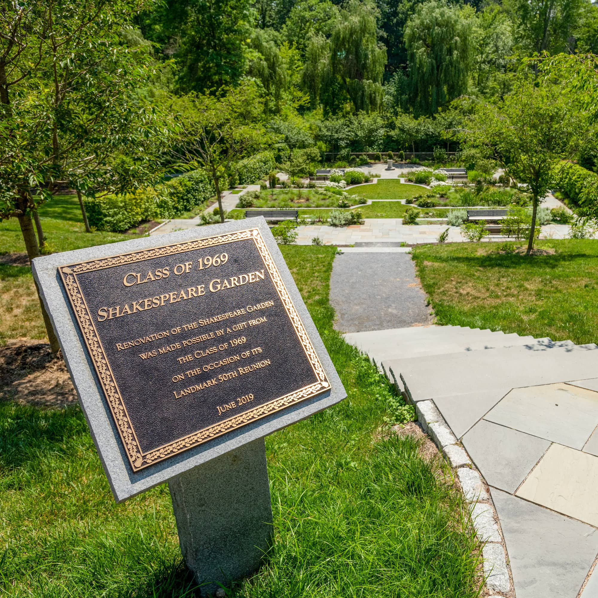 A plaque in front of the Class of 1969 Shakespeare Garden, a garden of different trees, flowers, and bushes laid out in multiple tiers on the Vassar campus, noting that the renovation of the garden was made possible by donations of the Class of 1969 on their 50th Reunion.
