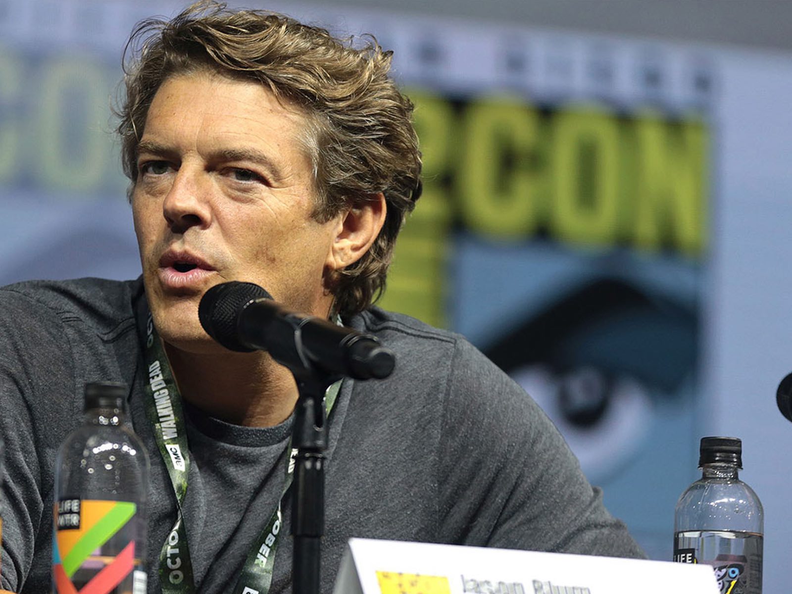 Jason Blum ’91, a person with brown hair, speaks in front of a microphone.