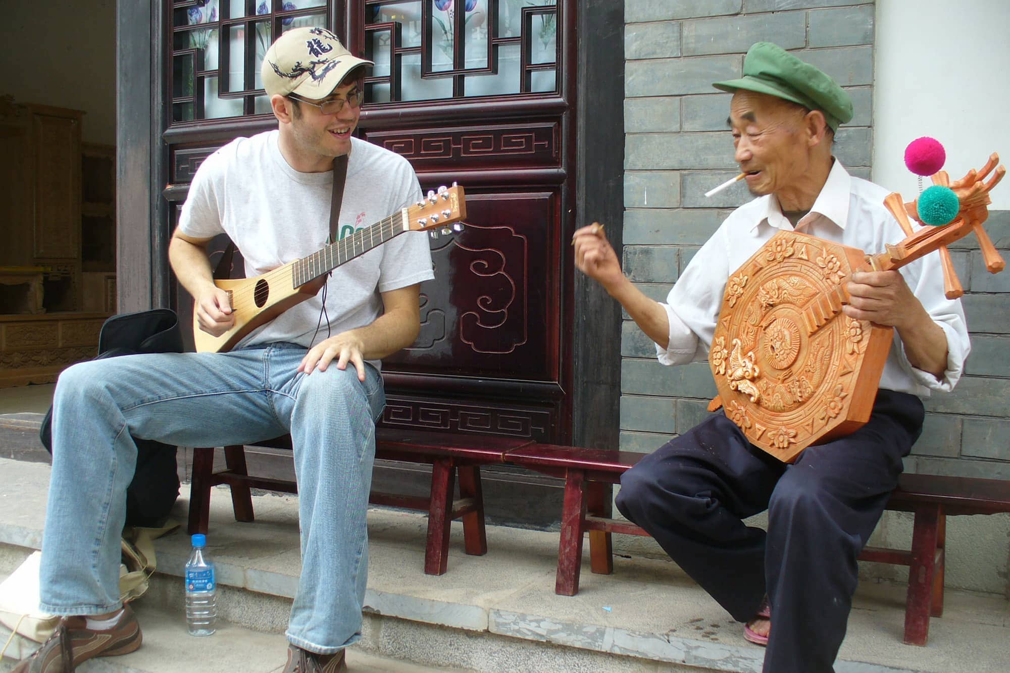 Two seated people playing stringed instruments.