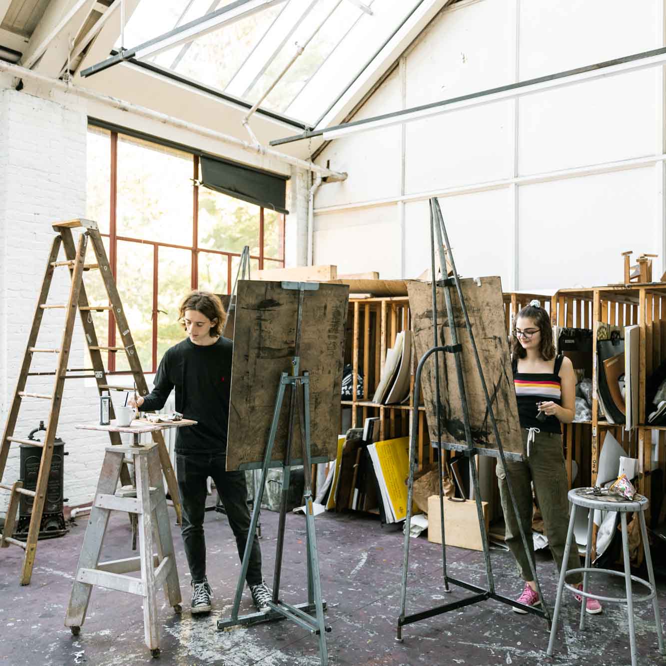 Students painting on easels in art studio.