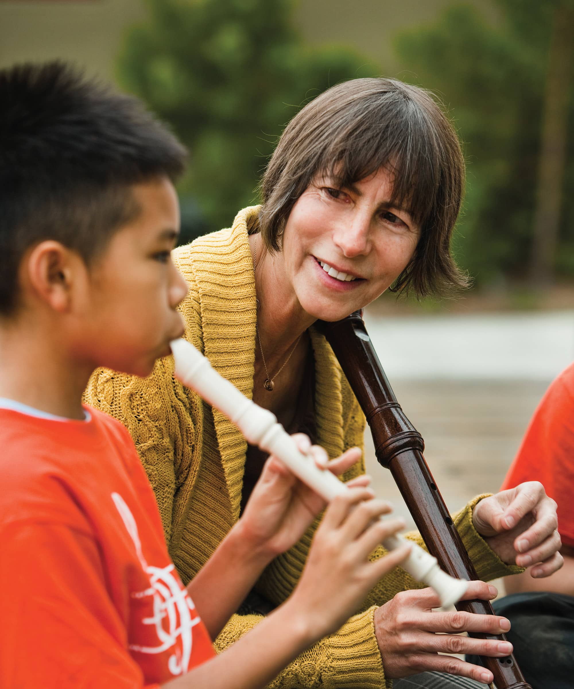 Adult with a flute watching a child play a flute