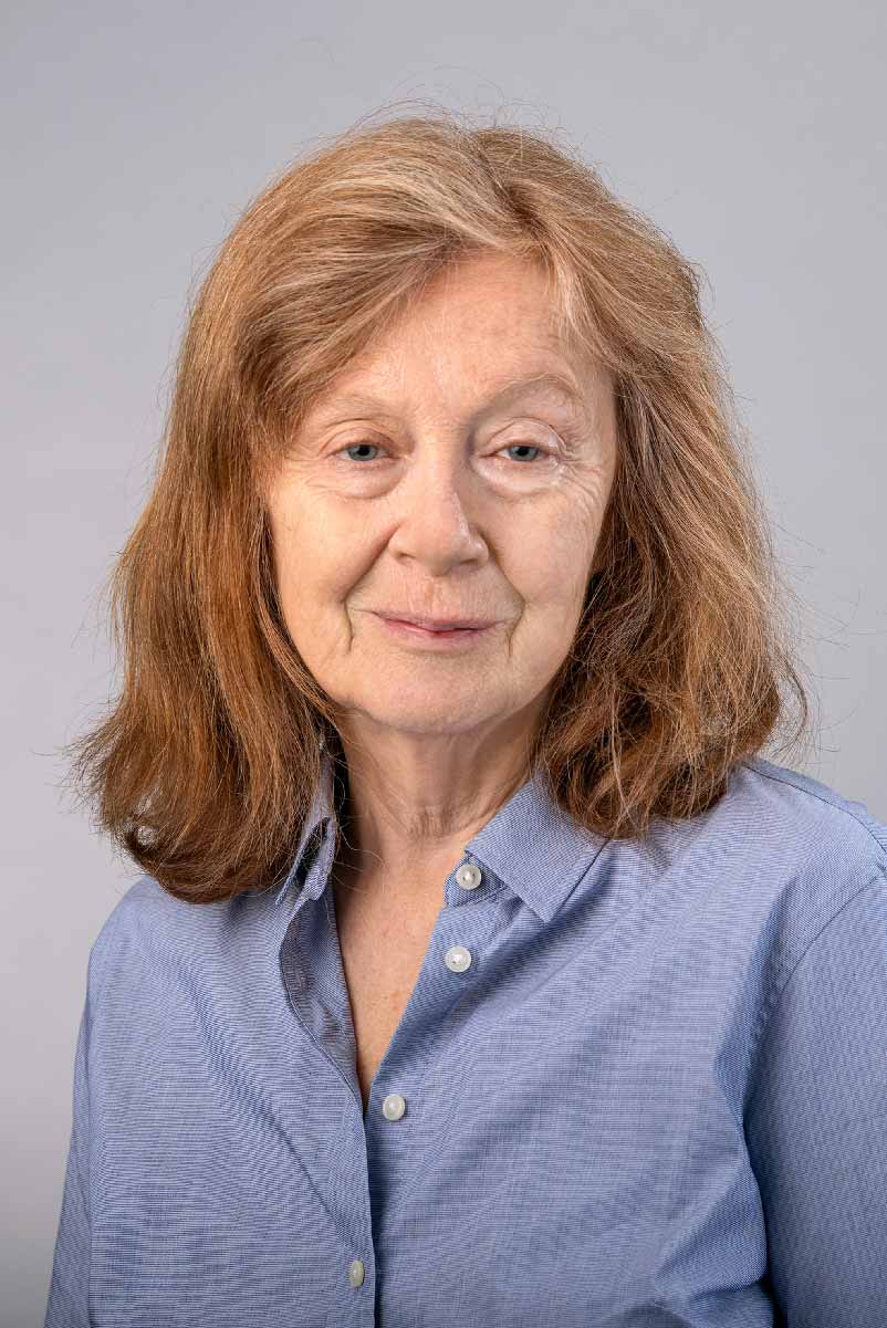 Jean M. Kane wearing a light blue collared shirt against a light gray background.