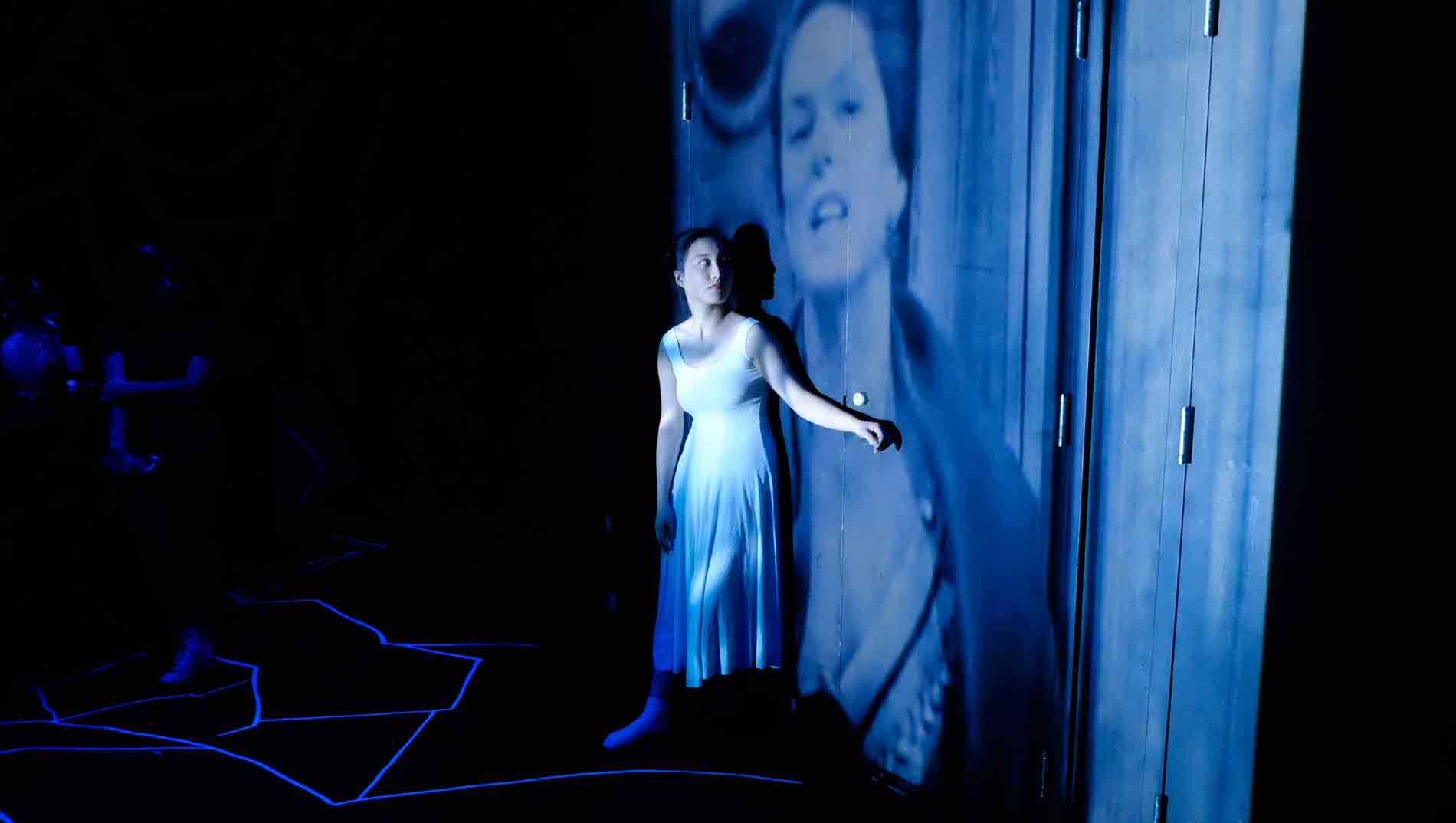 Lone performer gazes at an image projected on a wall