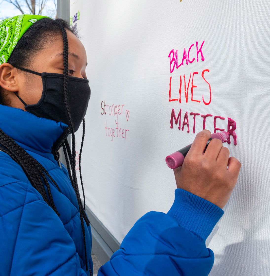 A girl writes "Black Lives Matter" on a board