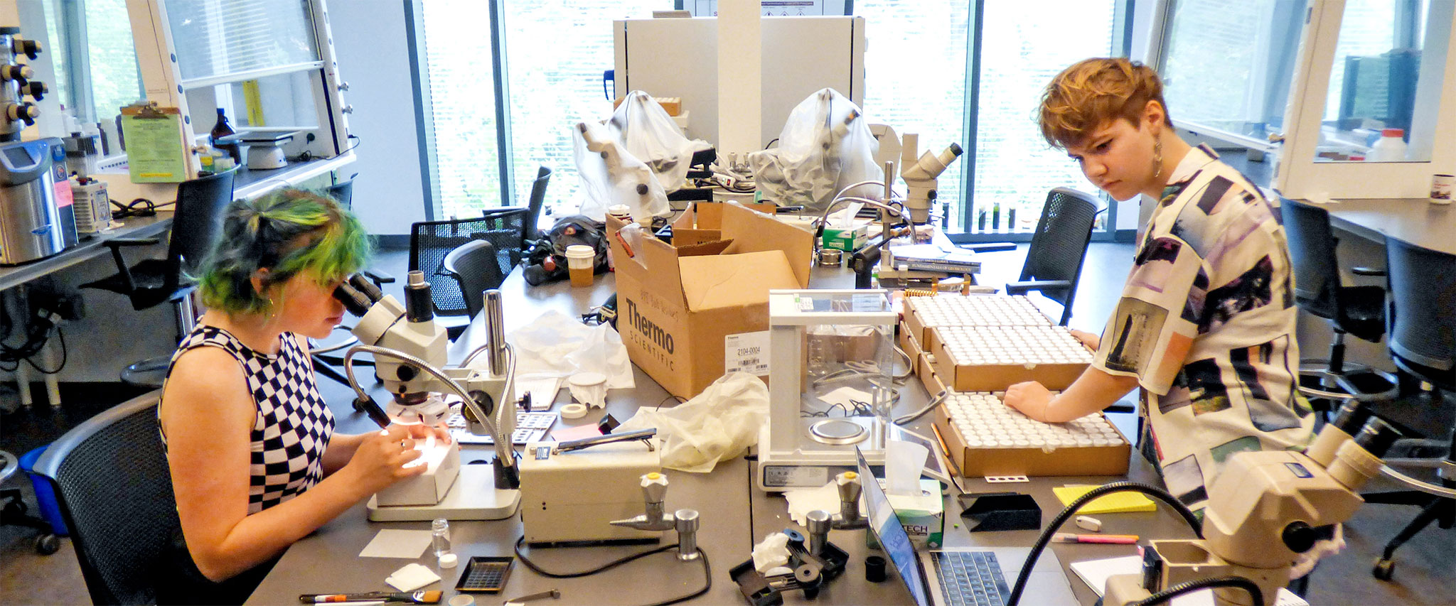 Carter Mucha ‘23 (left) and Elise Poniatowski ‘23 analyze tiny fossils from the Pacific Ocean floor in a lab in the Bridge for Laboratory Science