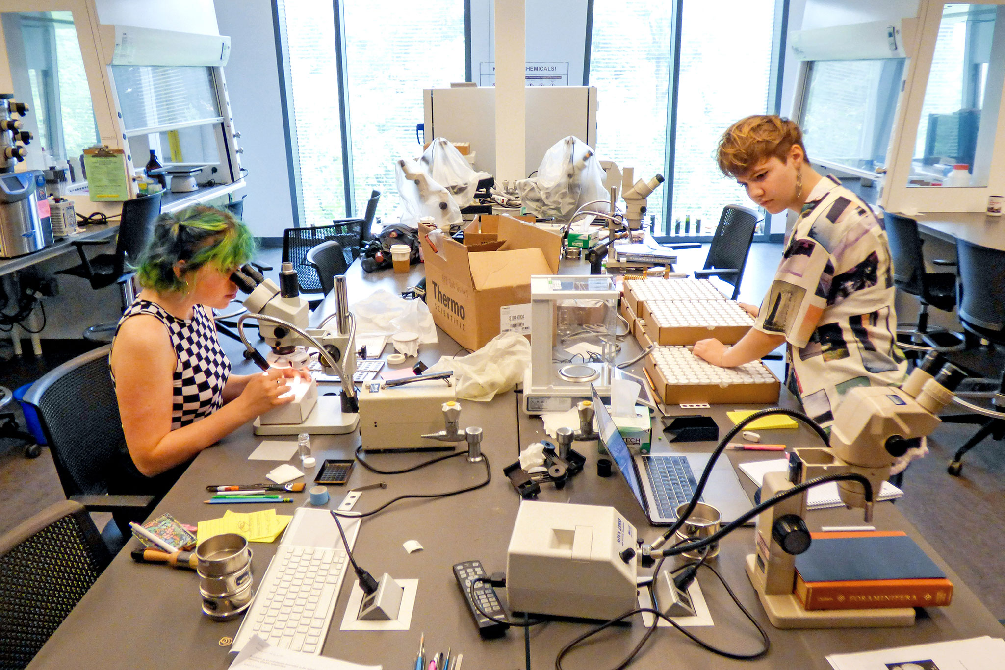 Carter Mucha ‘23 (left) and Elise Poniatowski ‘23 analyze tiny fossils from the Pacific Ocean floor in a lab in the Bridge for Laboratory Science