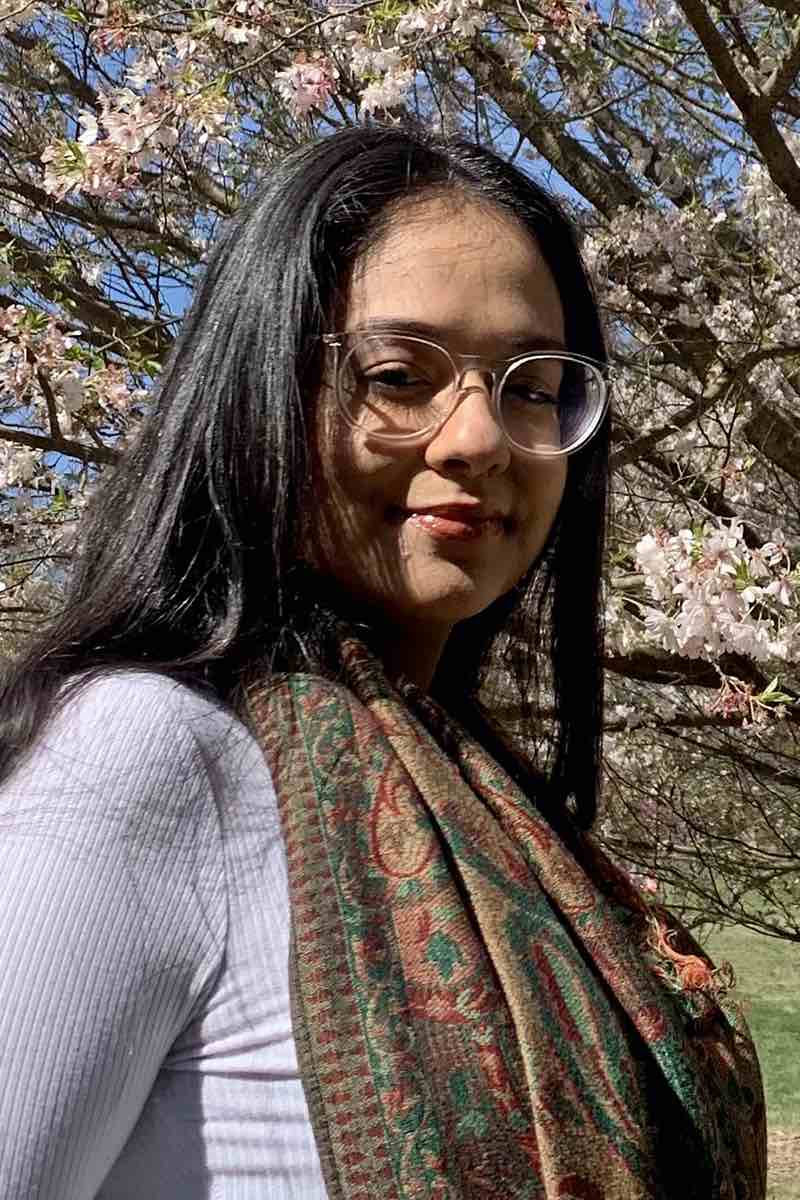 A girl with trees behind her.