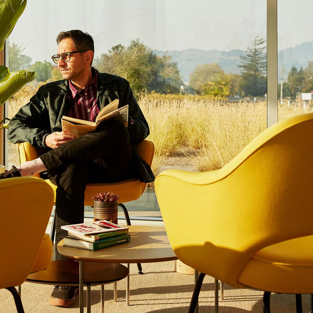 A photo of a person with short brown hair and glasses, reading a book and looking off into the distance.