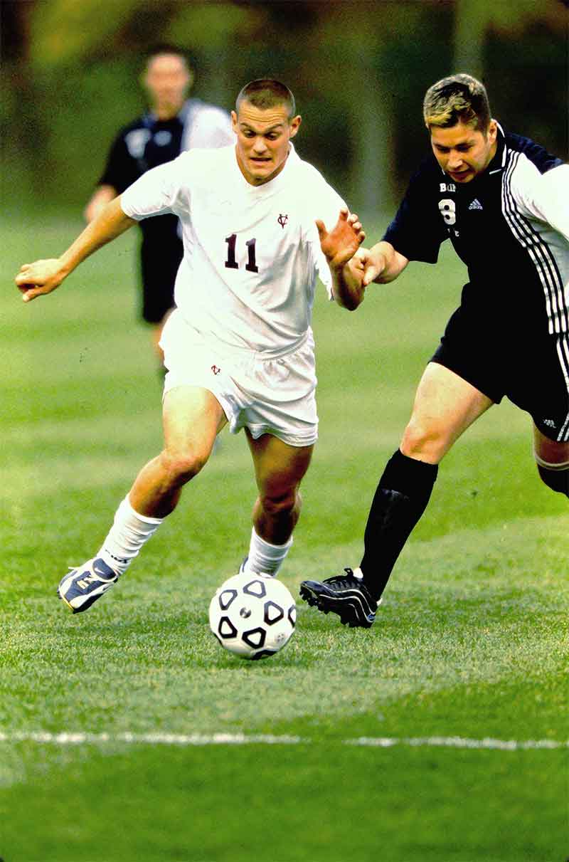 A man kicking a soccer ball during a game.