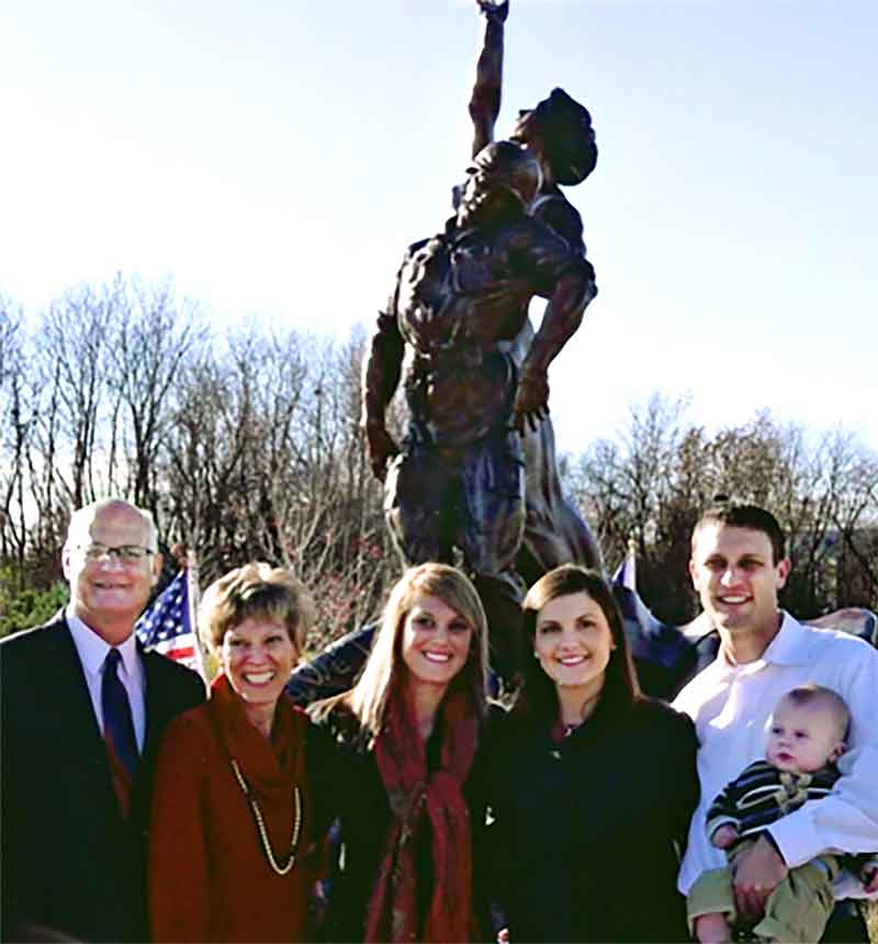 A group of people stand in front of a statue.