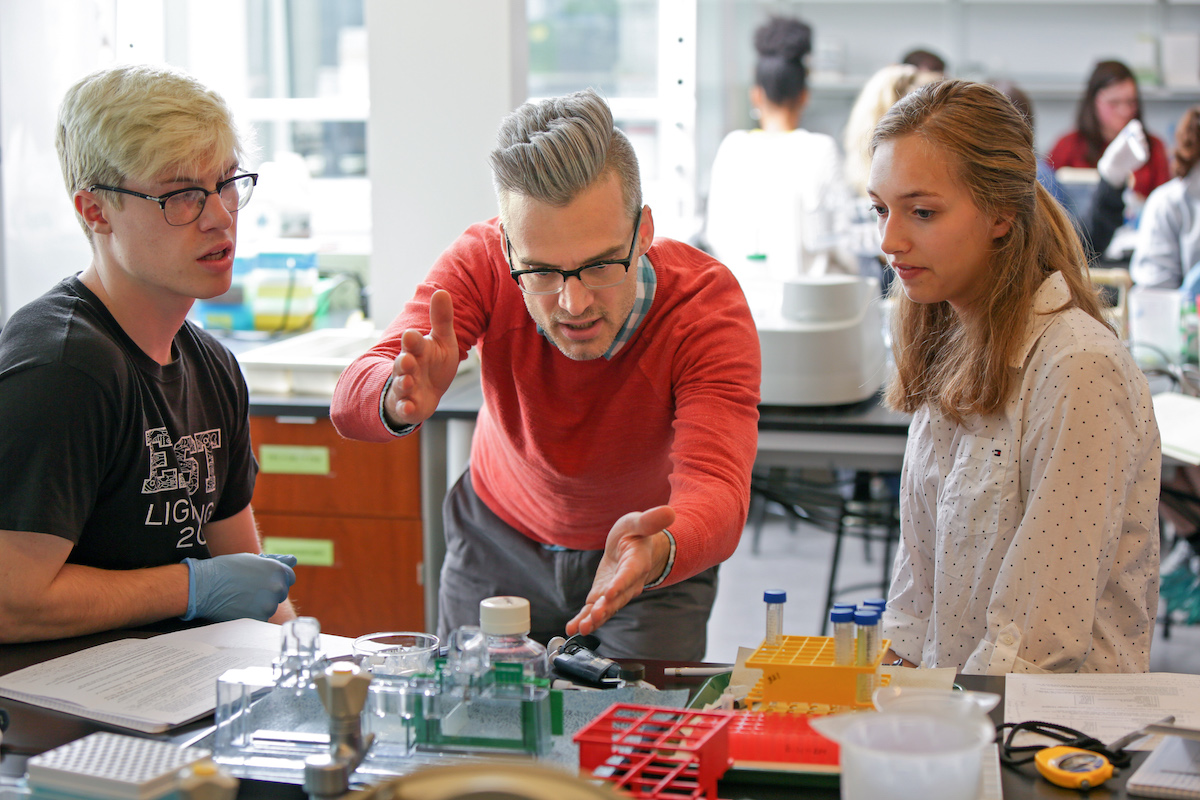 Assistant Professor of Biology and Biochemistry Colin Echeverría working in a class with two students