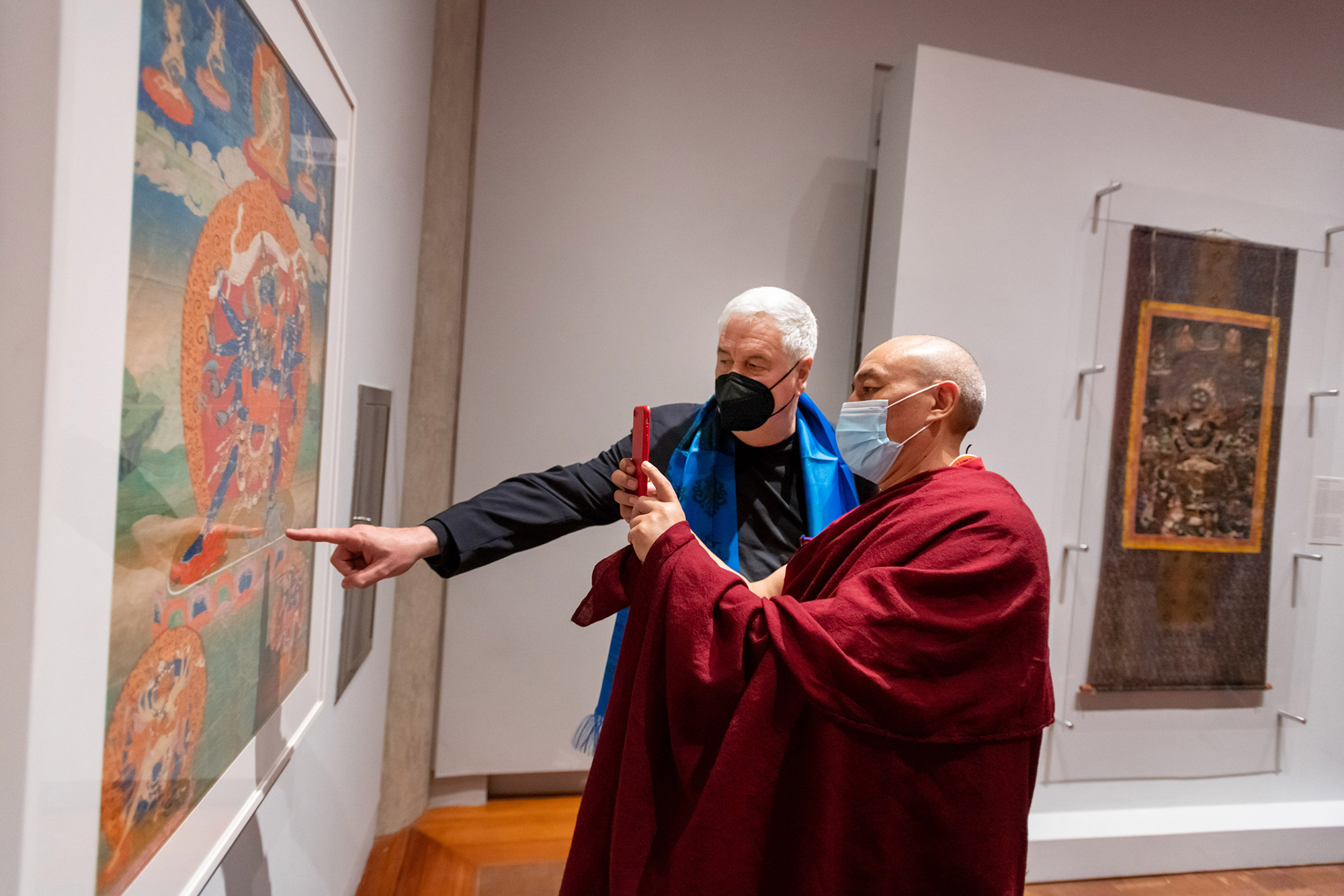 Jack Shear (left), donor of the exhibit, discusses the intricate artwork of a Thangka, a religious painting on cloth, with Lama Topgyal.