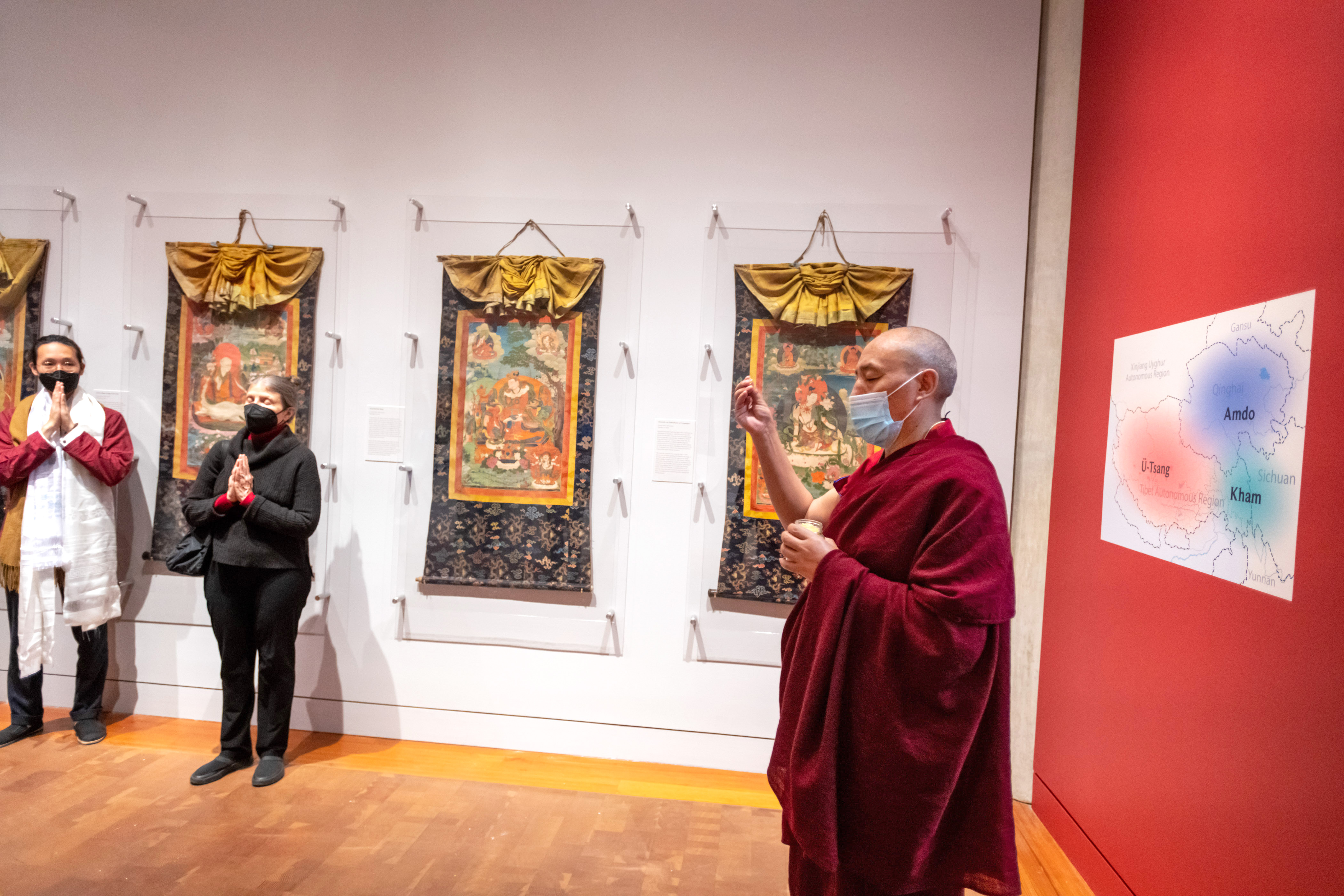 With a small handful of consecrated rice, Lama Tashi Topgyal blesses one of the works in the exhibit Mystery and Merit: Tibetan Art from the Jack Shear Collection, at the Loeb.