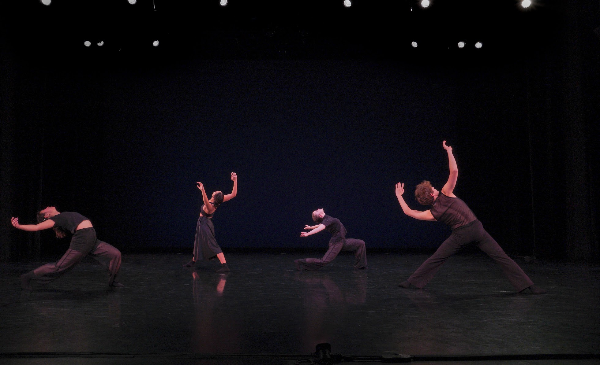 Four dancers dressed in black perform choreography by Kirven Boyd
