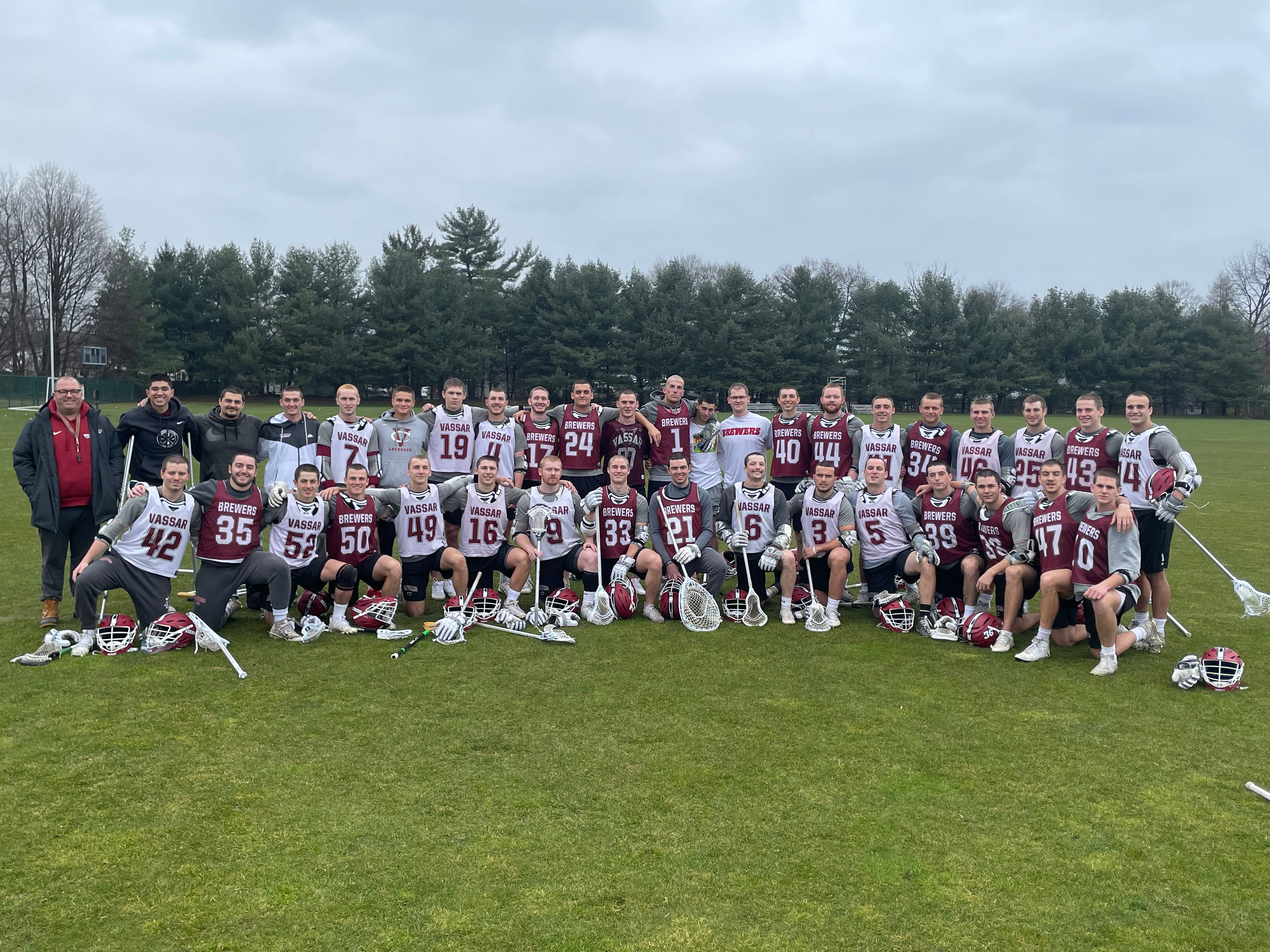 the men's lacrosse team posing with shaved heads in an outdoor group photo