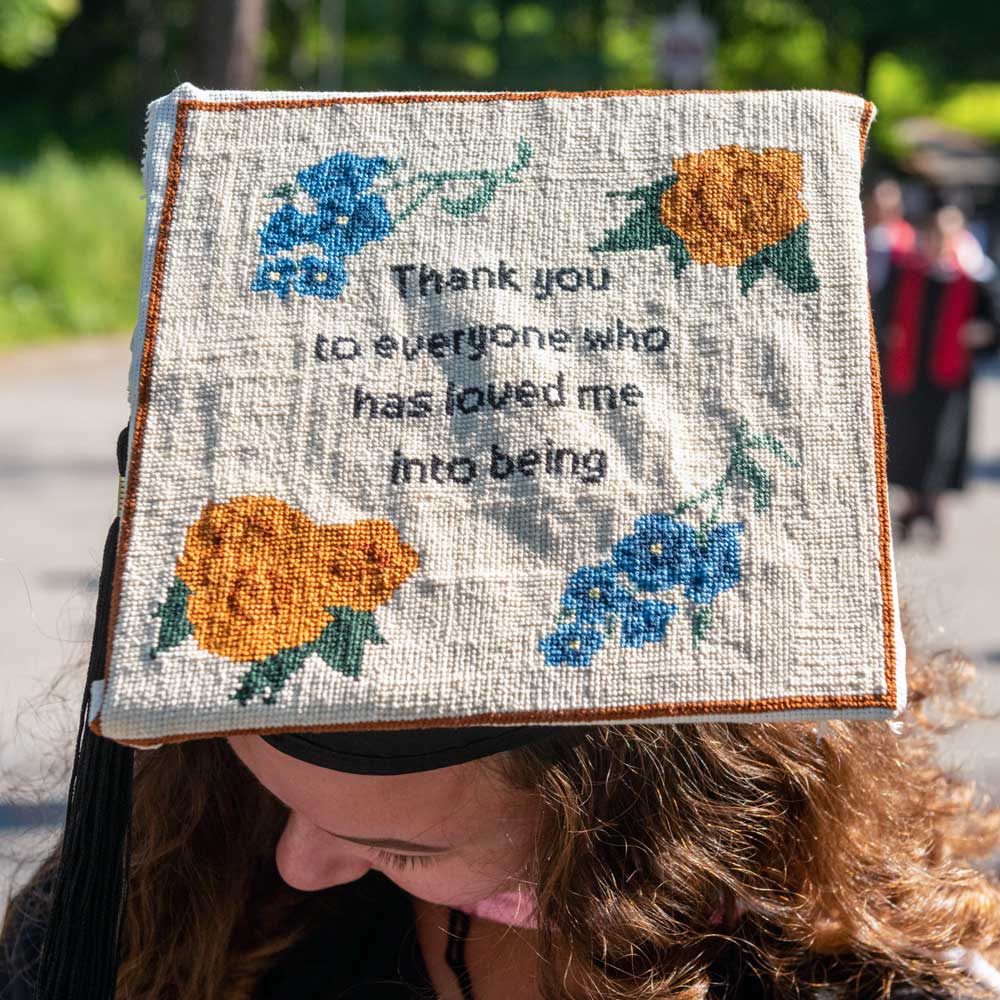 An embroidered sampler on a mortarboard with the words "Thank you to everyone who has loved me into being"