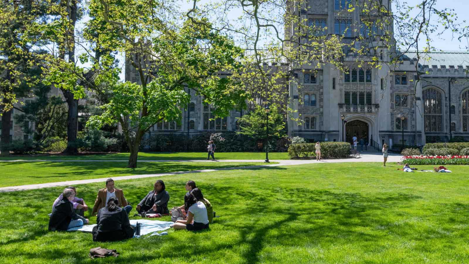 Group of people seated on a lawn in front of Thompson library on Vassar campus