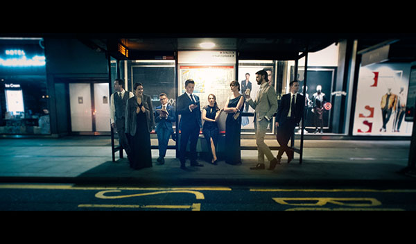 members of the vocal ensemble VOCES8 standing in an outdoor bus shelter at night