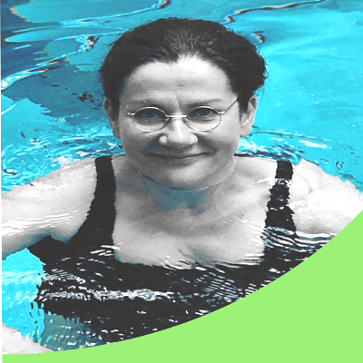 a closeup portrait of a smiling, dark-haired woman wearing a black one-piece bathing suit in a swimming pool