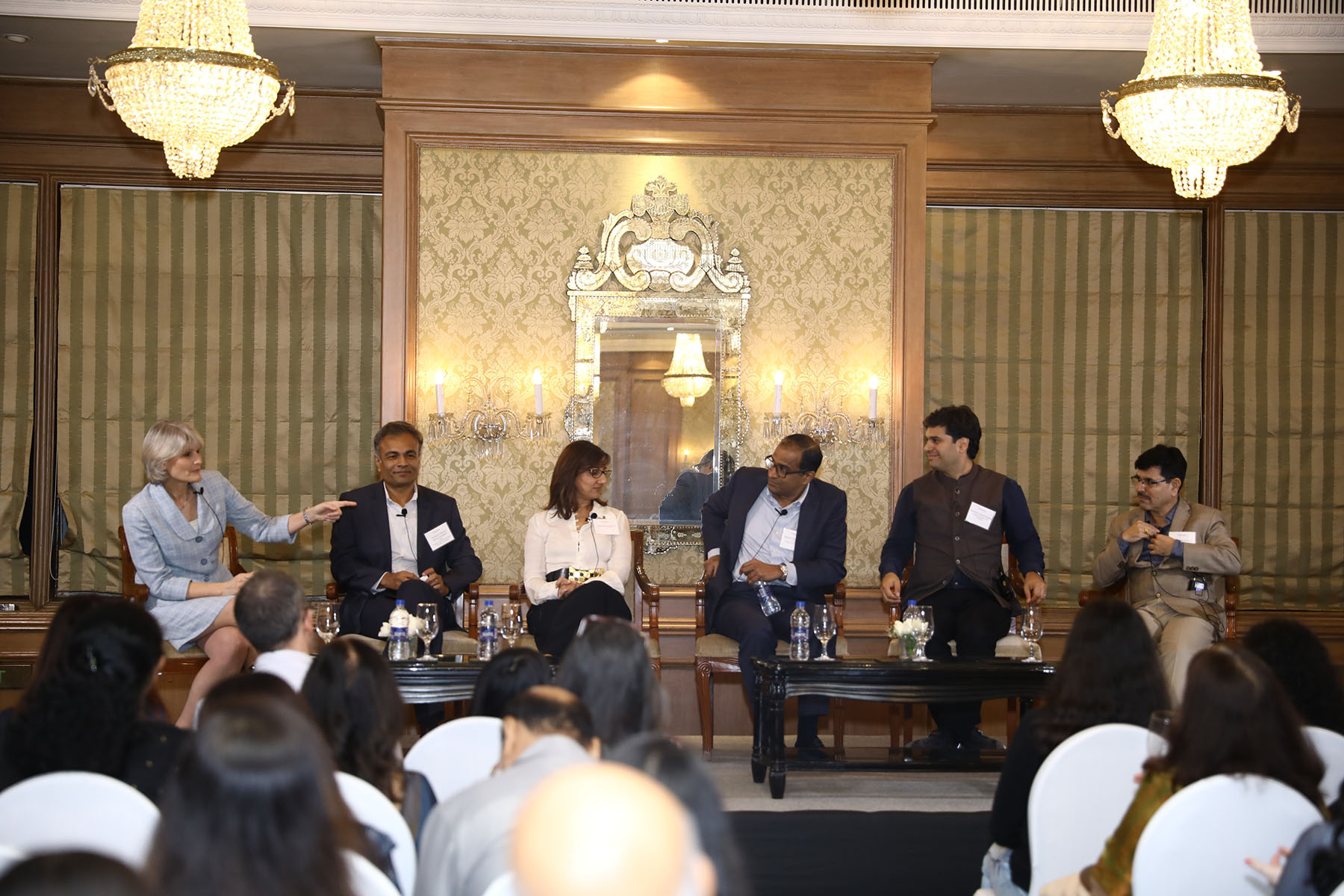 President Bradley seated with a panel of Indian scholars and scientists at tables in front of an audience.