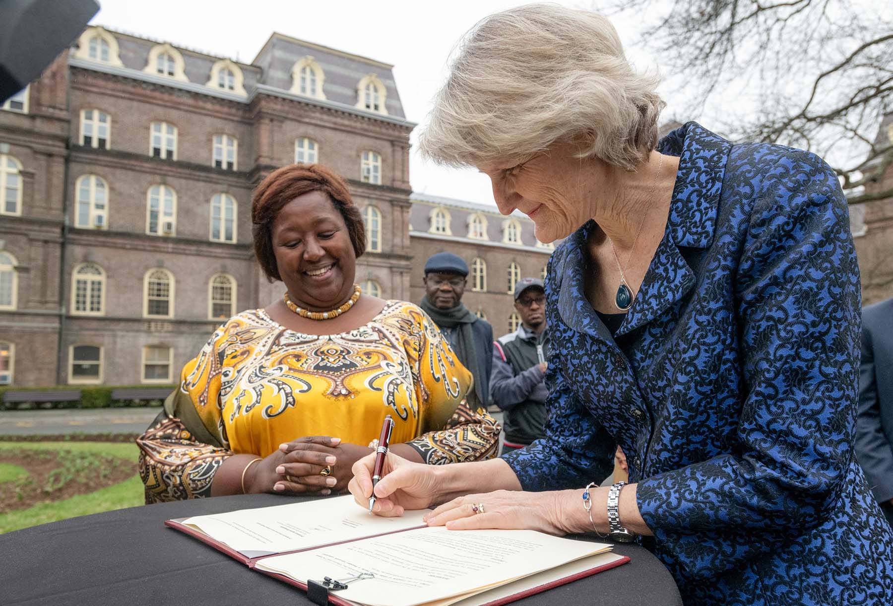 President Bradley, signing an agreement, and Dr. Agnes Binagwaho, Vice Chancellor of the University of Global Health Equity, standing outside of Main Building