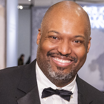 Damon Johnson '02 in black tie, smiling at the camera.