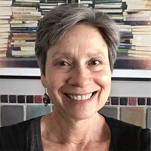 Historian Dora Apel seated in front of a shelf stacked with books.