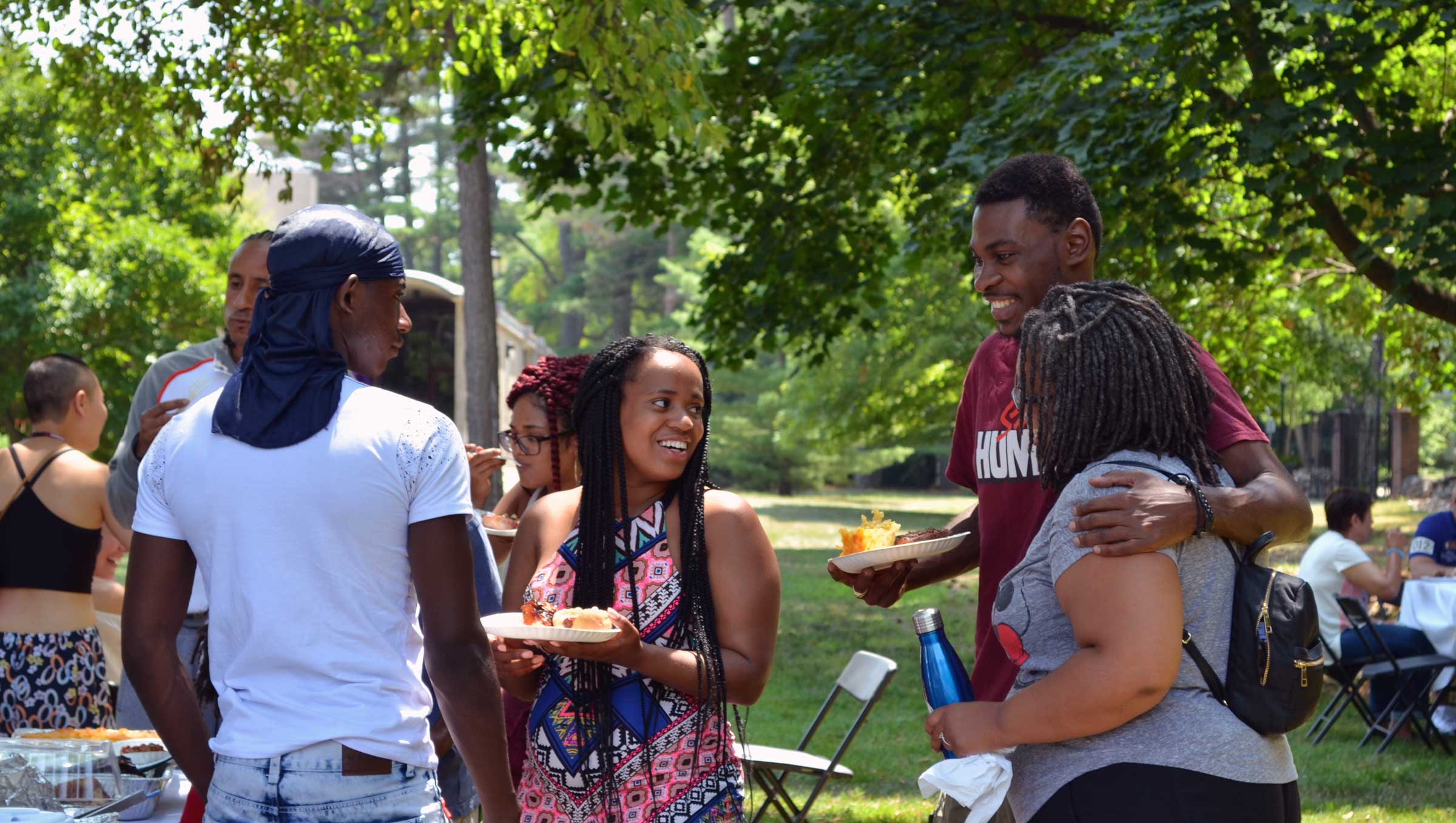 Group of four people standing and smiling outside at a barbecue