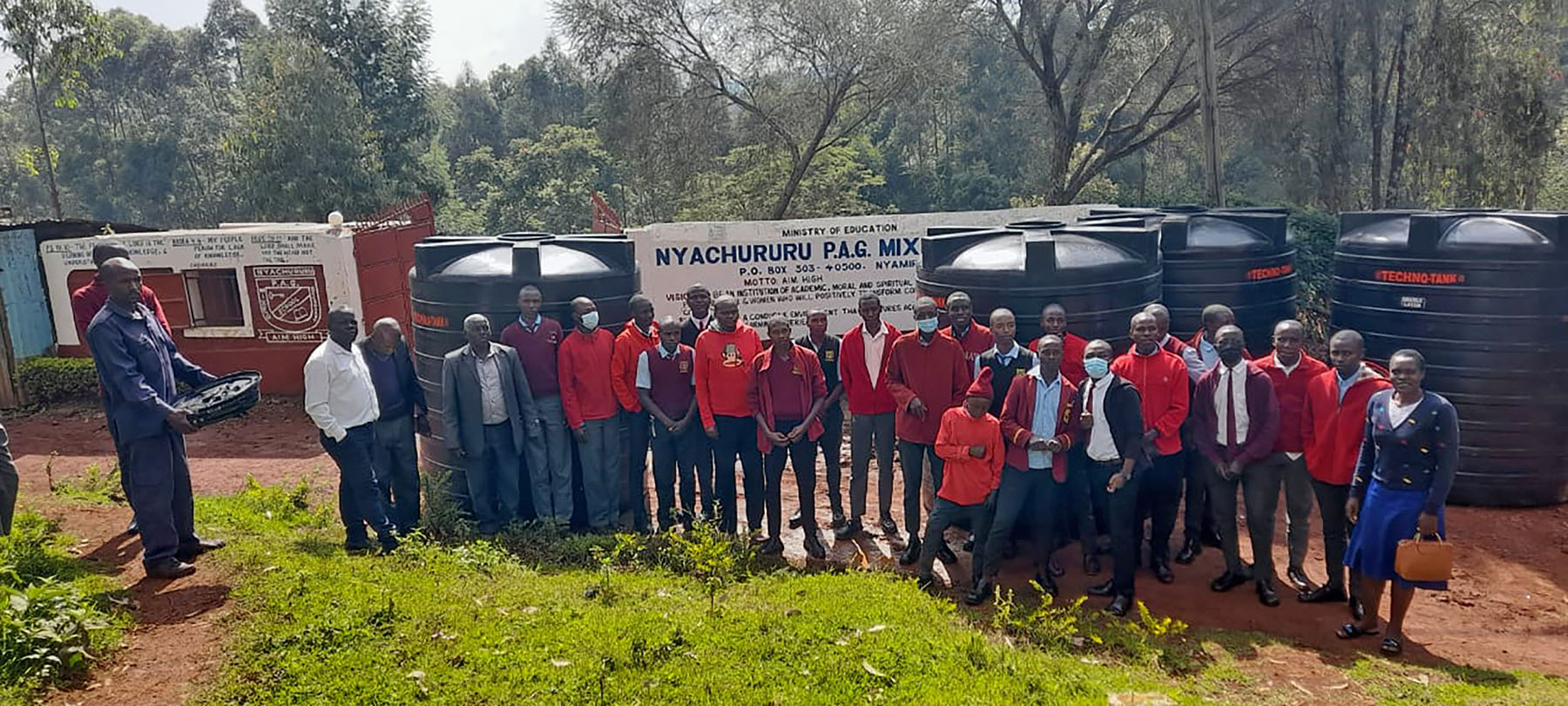 Students, teachers and administrators from secondary schools in the Kenyan village of Bosamaro standing in a group photo in front of water systems that were built by workers